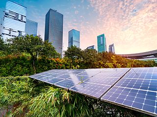 Solar panels in a city. Skyscrapers can be seen in the background.