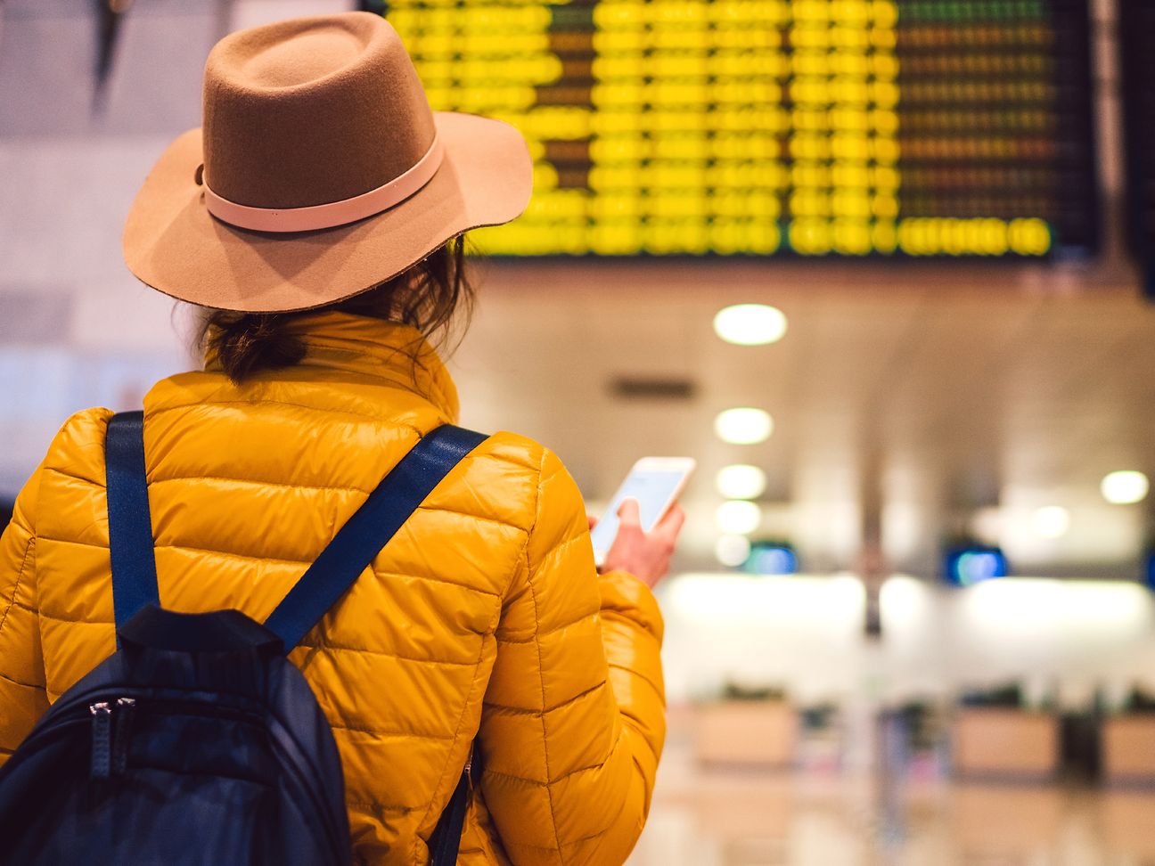 Schmuckbild: Frau vor Anzeigetafel Flughafen.
