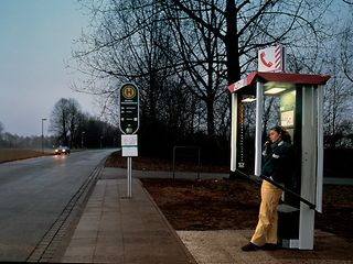 Twilight view of a telephone booth with a person.