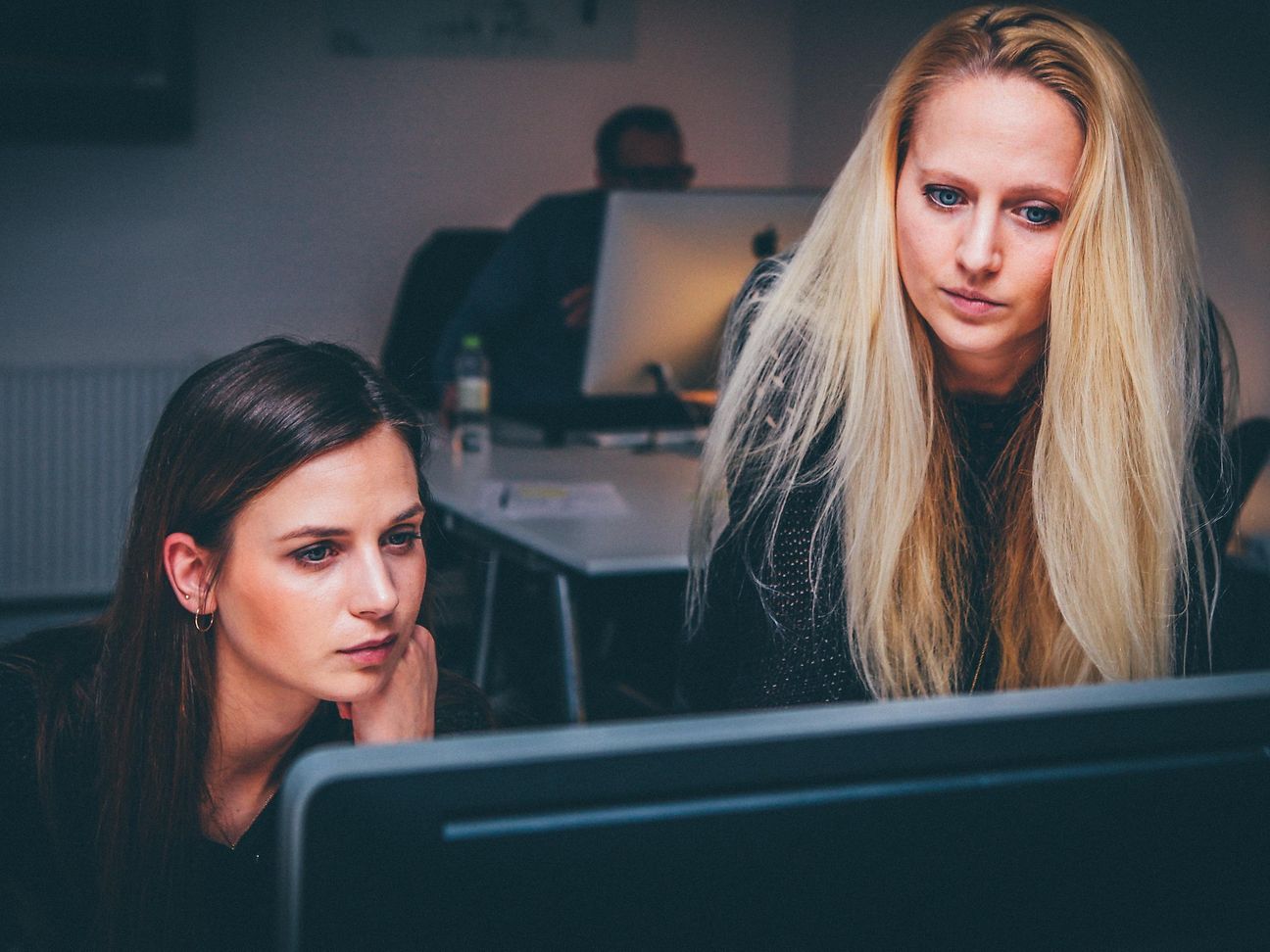 Zwei Frauen arbeiten gemeinsam konzentriert am Bildschirm.
