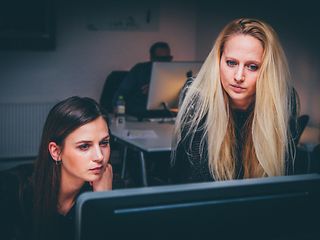 Two women work together on the screen in a concentrated way.