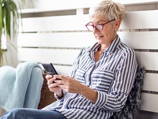 Eine ältere Dame führt ein Telefonat mit dem Handy.