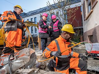 Telekom-Experten und Monteure der Tiefbaufirma Leonard Weiss vor einem Bagger. 