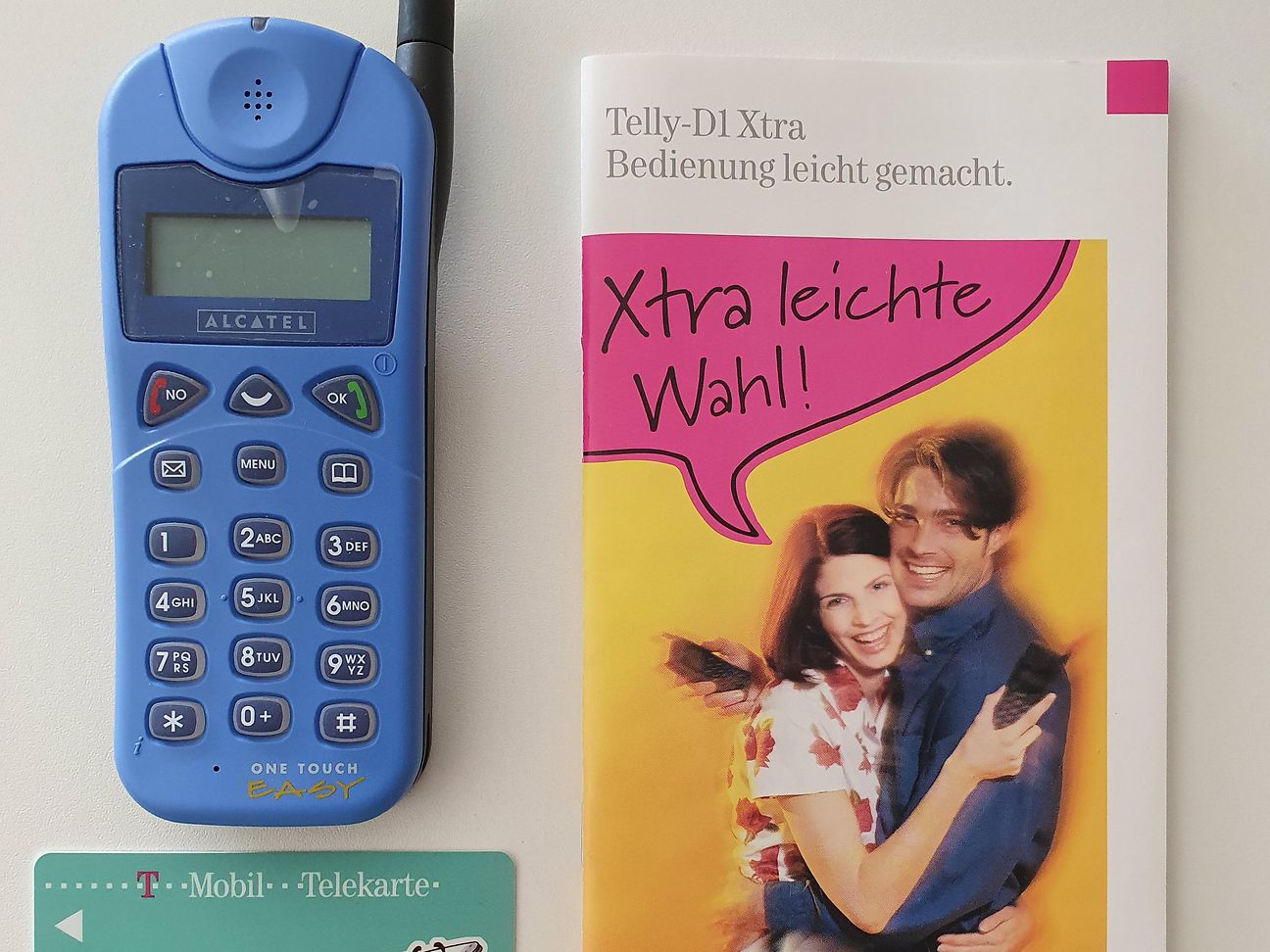 Das erste Prepaid-Paket der Telekom: Alcatel-Handy, Flyer und SIM-Karte. 