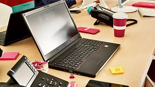 Desk with laptop, keyboard, office utensils
