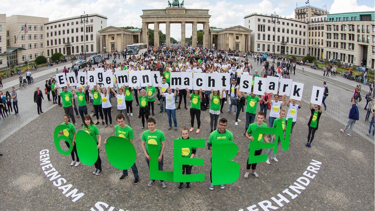 Very many people stand in front of the Brandenburg Gate in Berlin. 