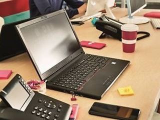 Exemplarischer Arbeitsplatz mit Laptop und Telefon