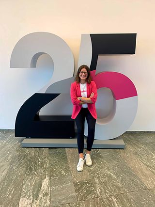 Woman stands in front of a big 25 on the occasion of Deutsche Telekom AG’s 25-year anniversary.