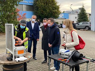 Ein Techniker der Firma RMK in gelber Jacke zeigt, wie Glasfaser gespleißt wird. 