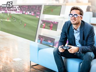 Man wearing glasses watching tv and also seeing additional content.