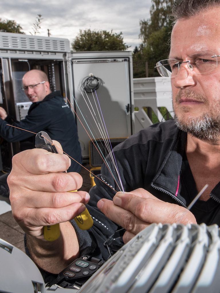 A technician cuts individual optical fibers using pliers.