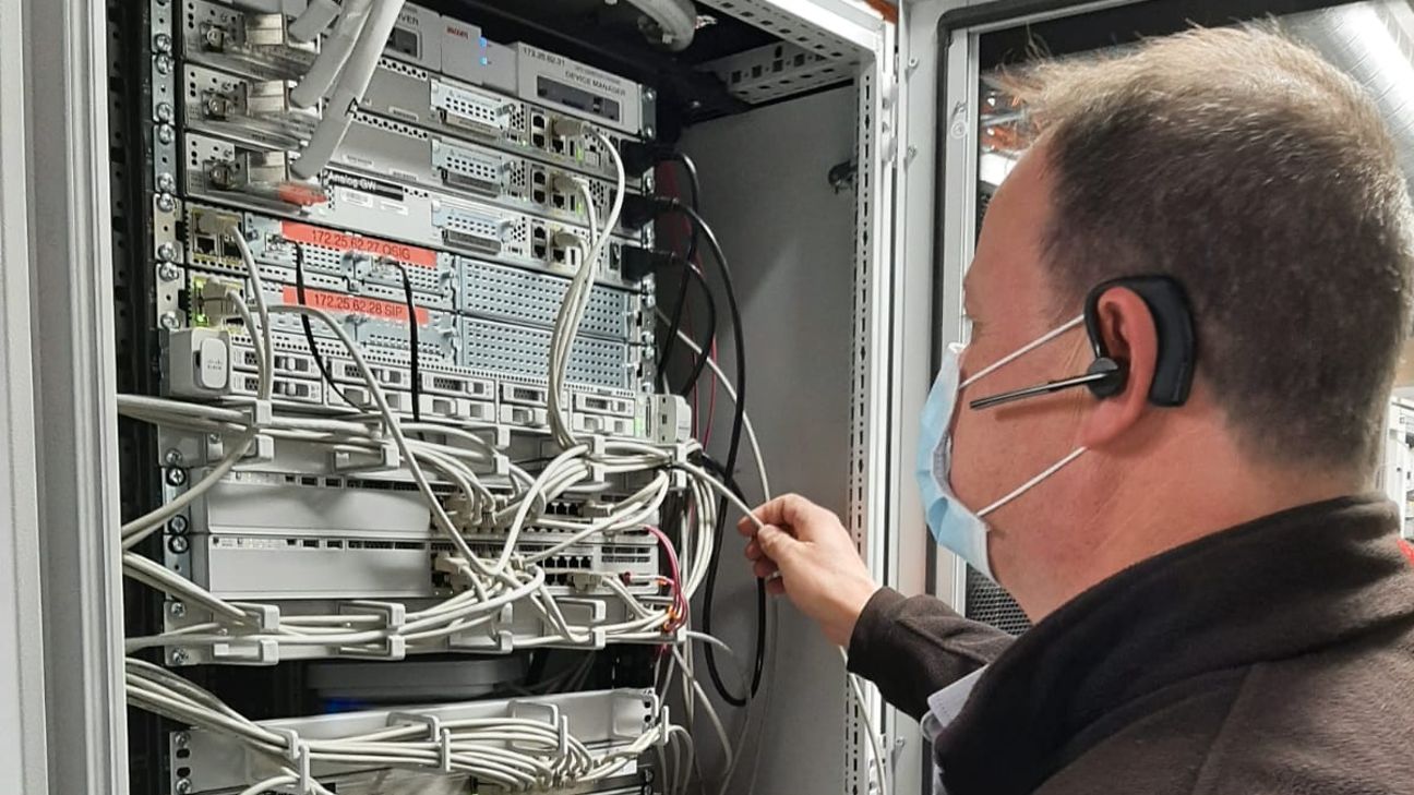 Ein Servicetechniker steht mit dem Rücken zum Betrachter vor einem Serverschrank. 