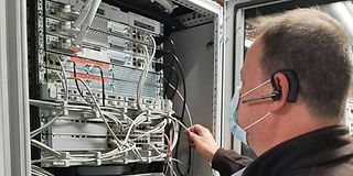 Ein Servicetechniker steht mit dem Rücken zum Betrachter vor einem Serverschrank. 