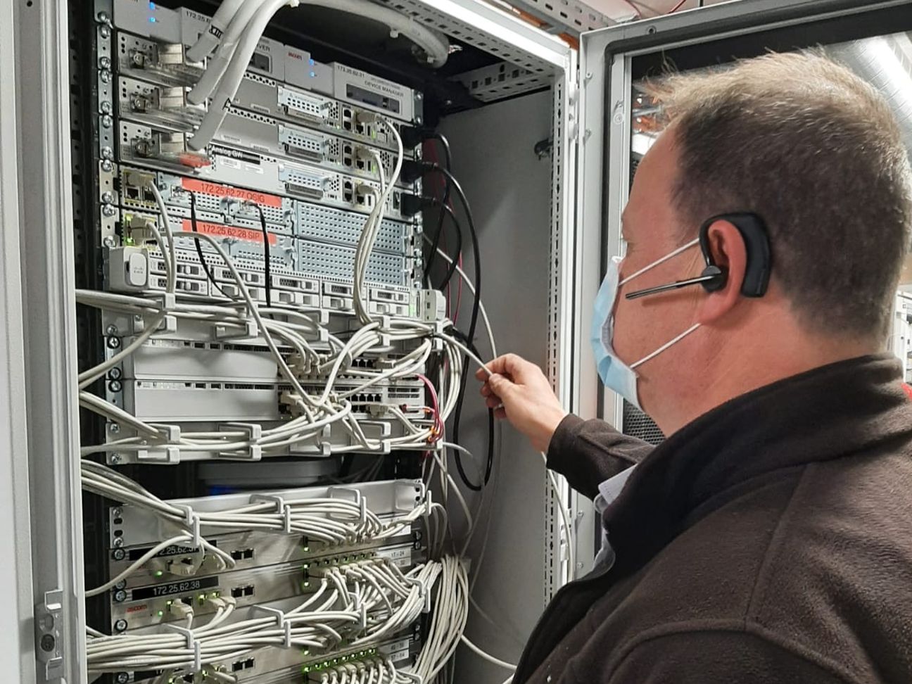 Ein Servicetechniker steht mit dem Rücken zum Betrachter vor einem Serverschrank. 