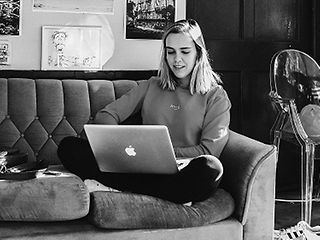 Studentin sitzt mit einem Laptop auf dem Sofa