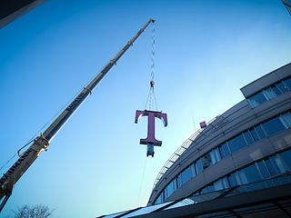 A crane lifts the T with a wight about 1.5 ton onto the roof of the Telekom headquarters.