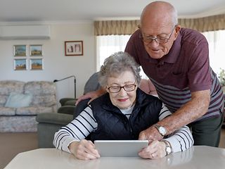 Ein älteres Paar schaut gemeinsam auf ein Tablet.
