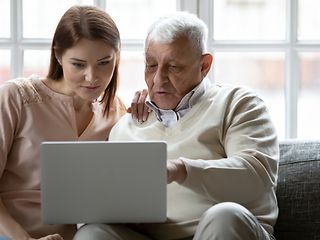 Junge Frau und ältere Mann schauen auf Laptop