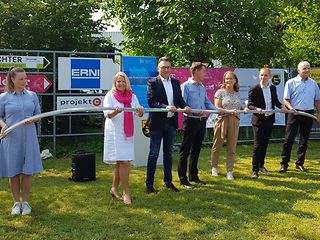 Personen stehen mit Abstand nebeneinander und halten gemeinsam mehrere Meter Glasfaserkabel in den Händen.