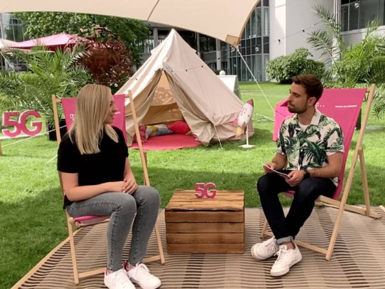 Zwei Telekom Mitarbeitende sitzen in sommerlicher Atmosphäre zu einem Interview zusammen.
