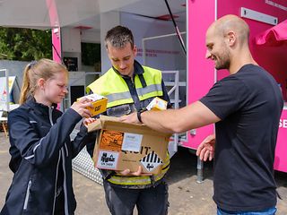 Drei Menschen schauen in eine Kiste mit Handys