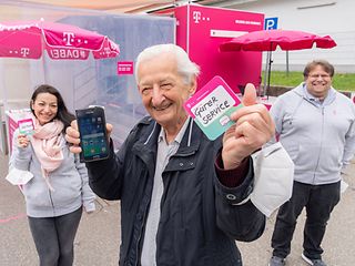 Ein Mann hält einen Bierdeckel in die Kamera, im Hintergrund das Serviceteam