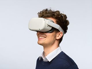 Ein Mann hat eine VR-Brille aufgesetzt und schaut lächelnd nach unten links