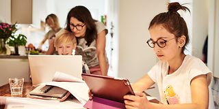 Familie beim Homeschooling am Küchentisch.