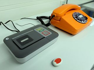 Ein orangefarbenes Telefon mit Wählscheibe neben einem Anrufbeantworter.