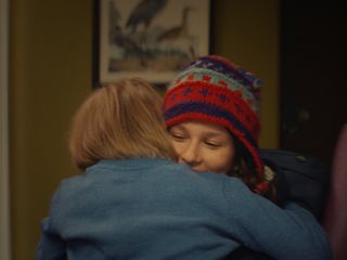 Exuberantly brother and sister fall into each other's arms at Christmas.