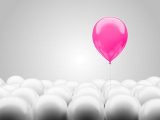 magenta colored balloon flies up from a large crowd of white balloons. 