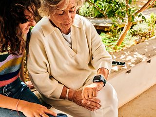 Ältere Dame zeigt Enkelin ihre Smartwatch. 