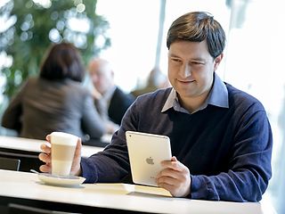 Lutz Schottenhammer trinkt einen Kaffee und liest auf einem iPad.