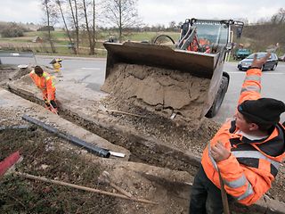 Ein Bagger schüttet Erde in eine Baugrube.