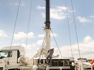 Bauarbeiter stellen einen Mast auf.