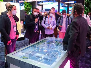 Ein Telekom-Mitarbeiter erklärt “Factory of the Future“. Dabei zeigt er auf das virtuell dargestellte 5G Campus-Netz. 