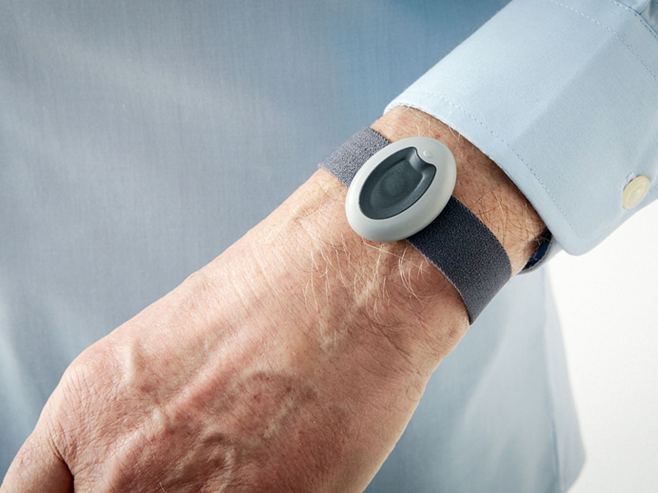 Ein Mann trägt einen Auslöser für den Hausnotruf als Armband 