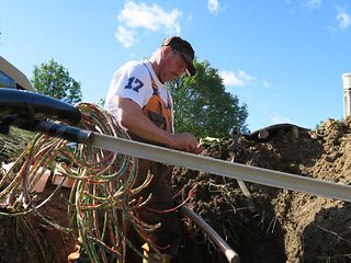 Ein Techniker verlegt Kabel in einer Grube.