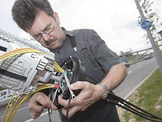 Ein Arbeiter der Deutschen Telekom verknüpft Kabel.