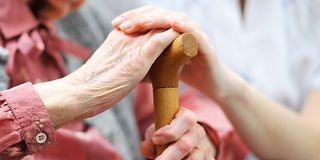 Younger hands hold the ones of an older woman
